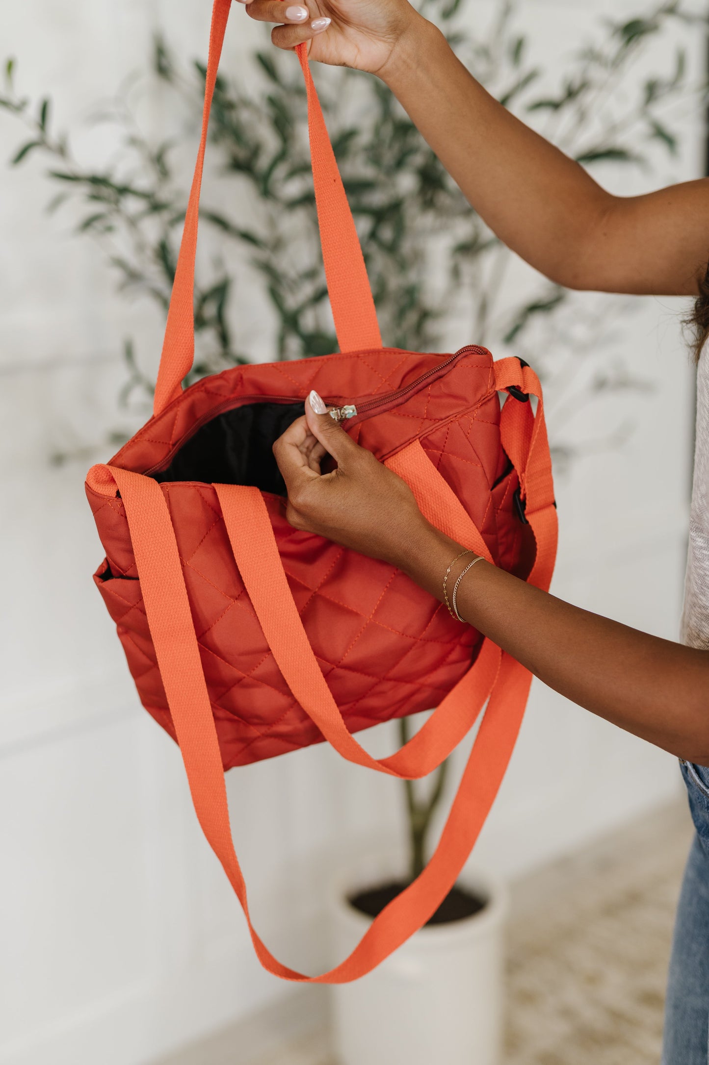 Close-up of Tallulah tote bag in tomato red highlighting zipper closure and quilted fabric detail.