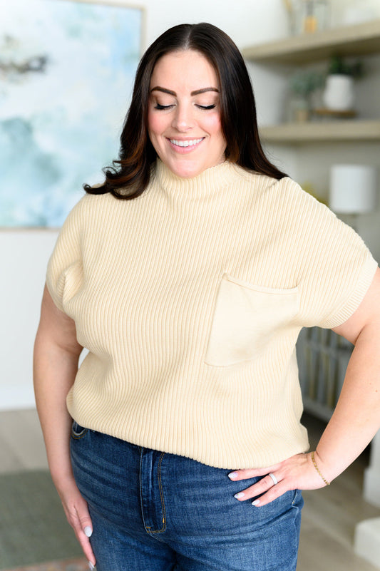 Plus size model wearing Lil Mock Neck Sweater in oatmeal with ribbed knit, patch pocket, and mock neckline.