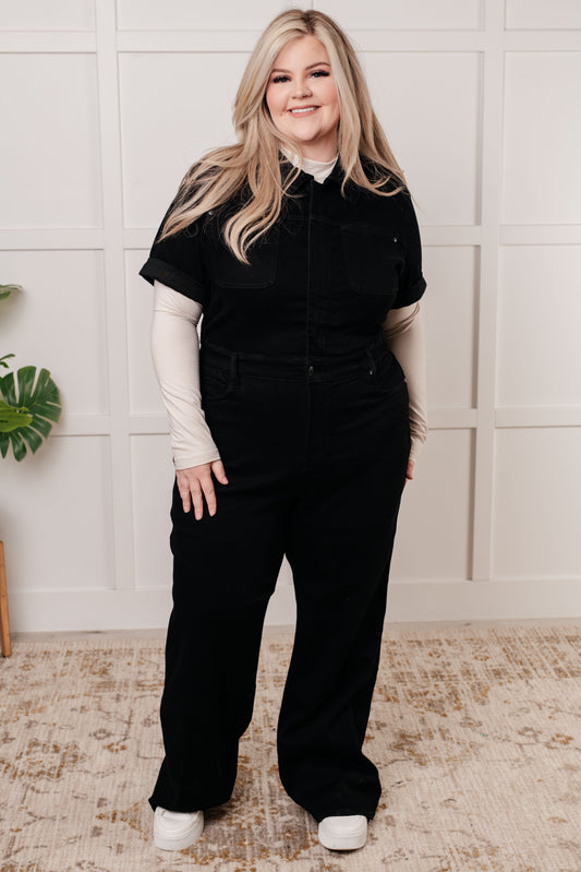 Plus size model front view wearing Timara Denim Jumpsuit in black, flattering tummy control and snap waistband