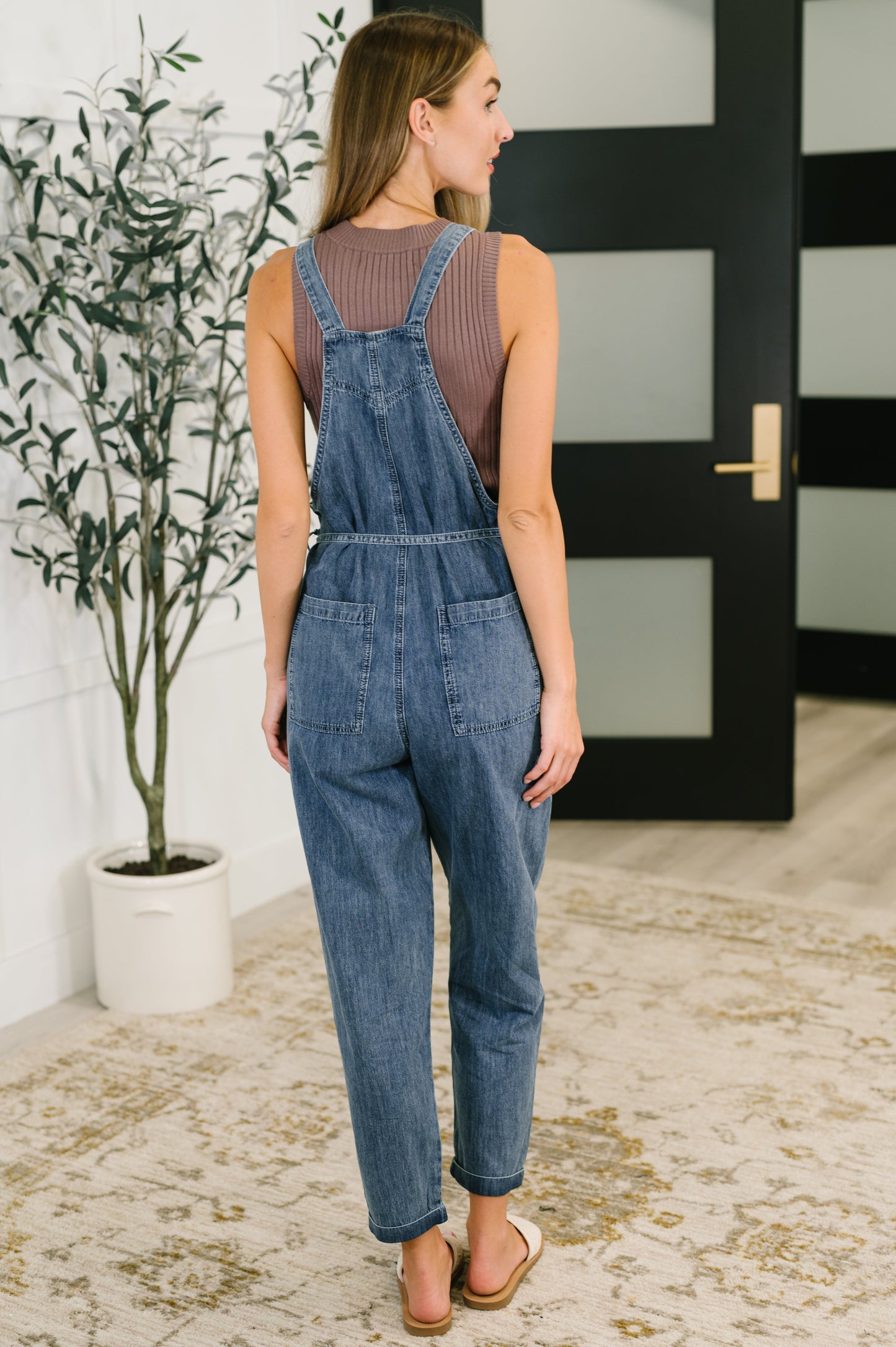 Back view of Tobin Waist Tie Overalls in chambray with cross straps, relaxed silhouette, and cuffed hems