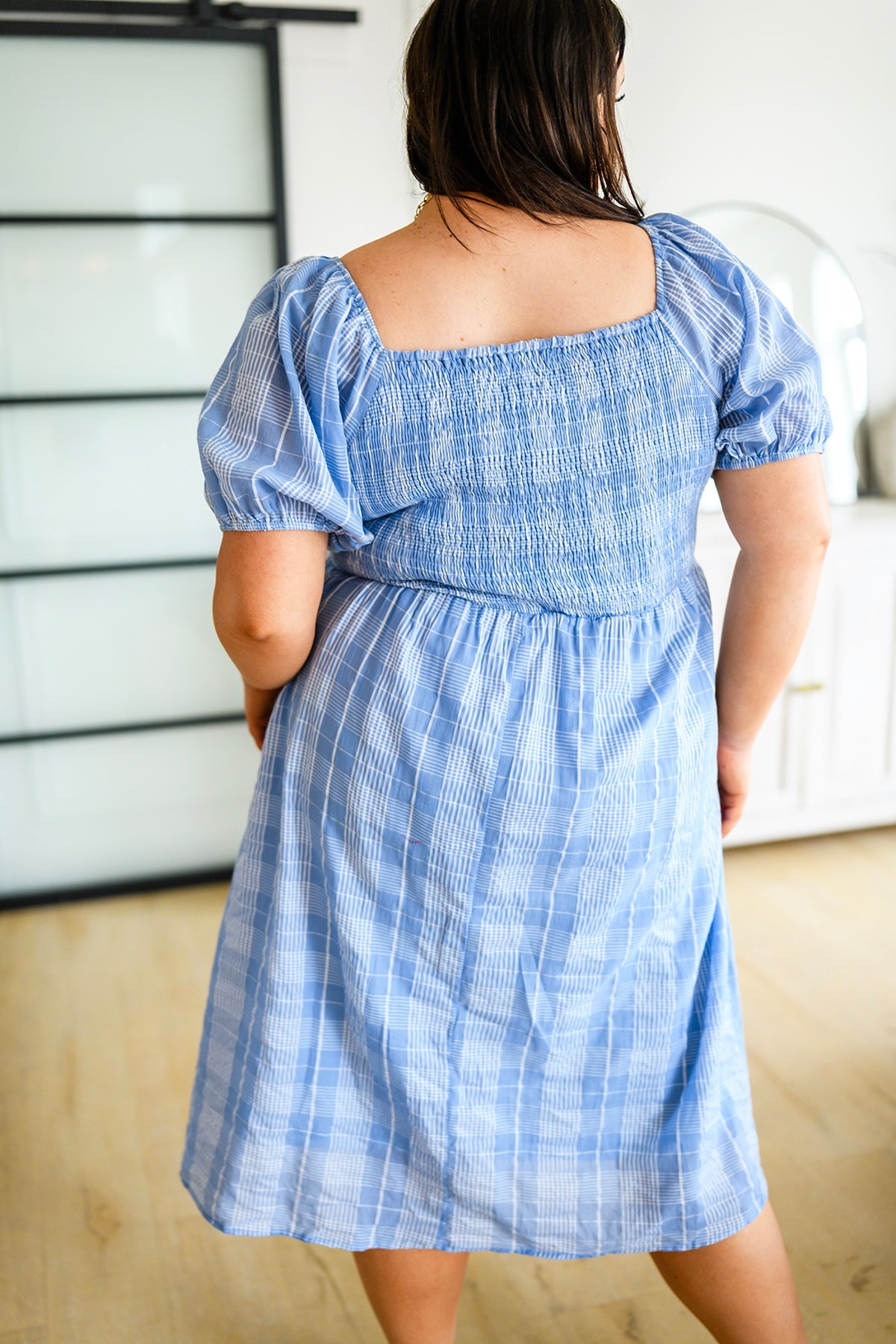 Plus size back view of Payson Puff Sleeve Dress showing smocked stretch fit, puff sleeves, and blue plaid midi skirt.