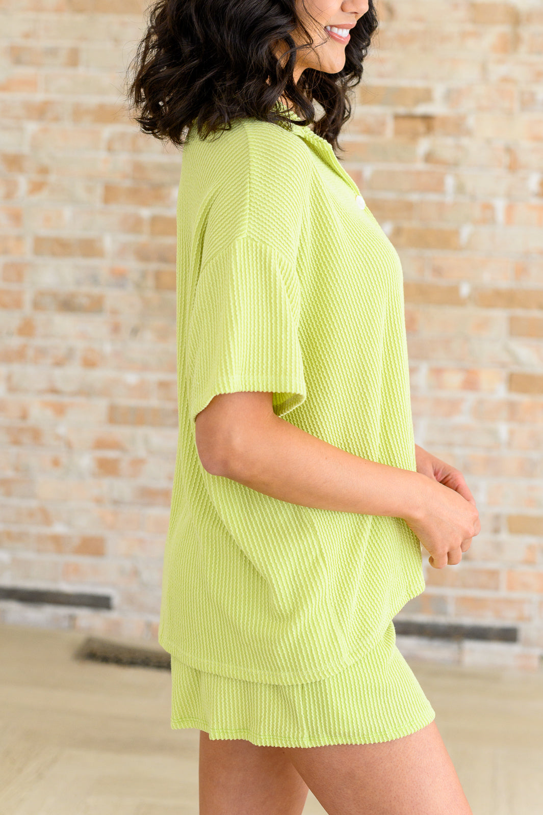 Side angle of Townes Ribbed Button Down Shirt in pear green textured knit, styled with matching shorts