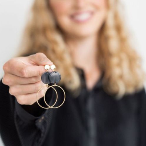 Woman holding Sadie Earrings – Black, highlighting gold and acrylic design.