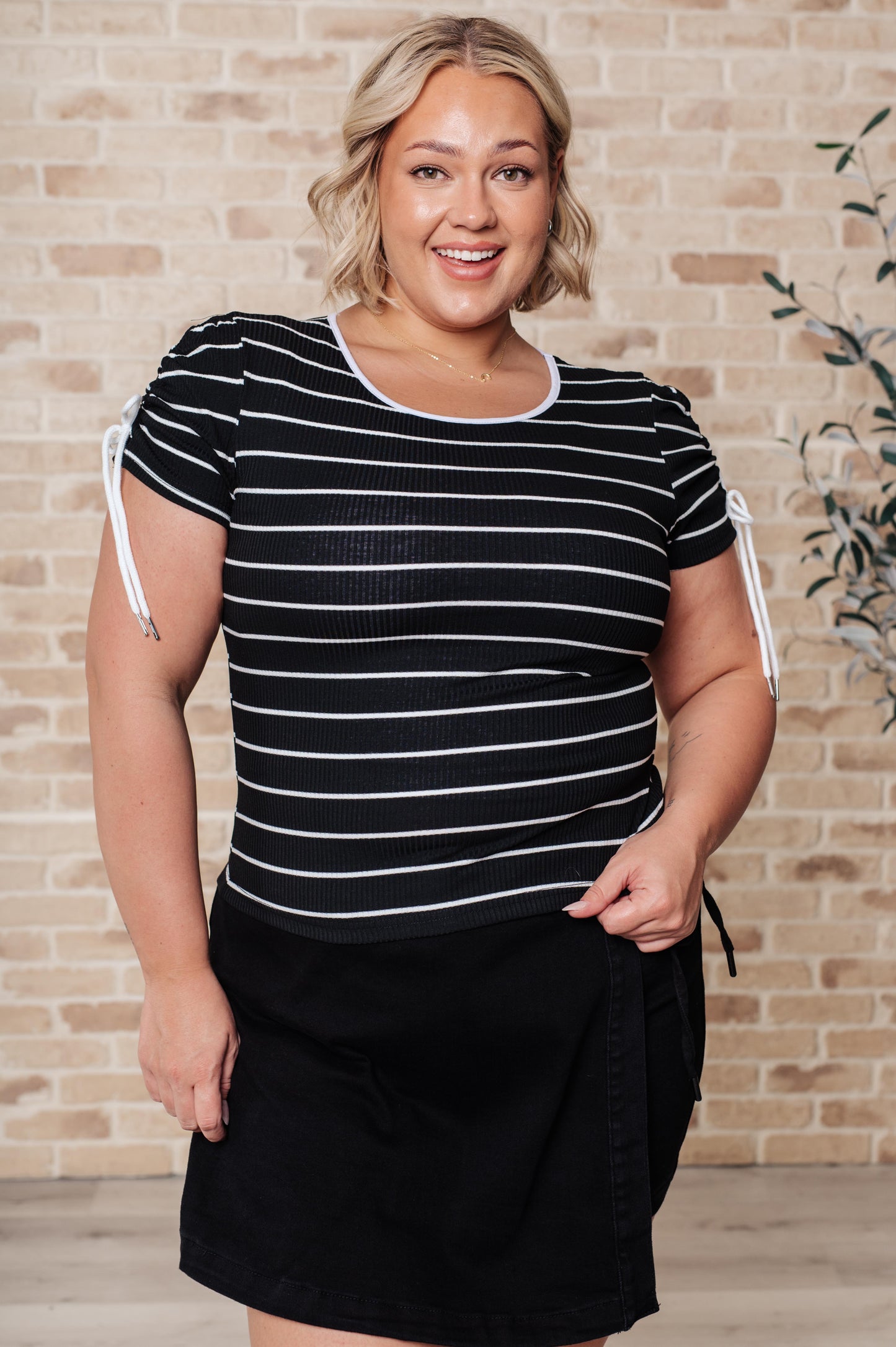 Plus sized Sylvia Striped Top in black and white featuring ribbed knit fabric, a round neckline, and short sleeves with a functional drawstring detail.