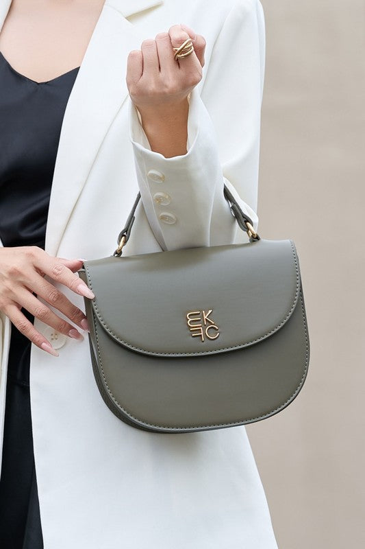 Woman holding olive Heloise Crossbody Bag by top handle in crook of arm.