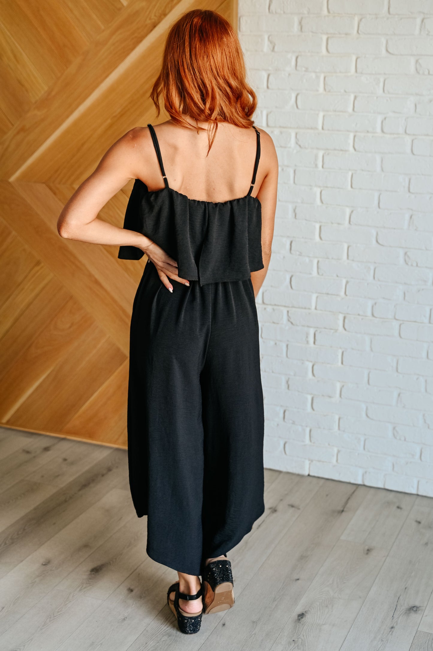 Back view of Sahar Black Jumpsuit with elastic neckline and tiered bodice detail.
