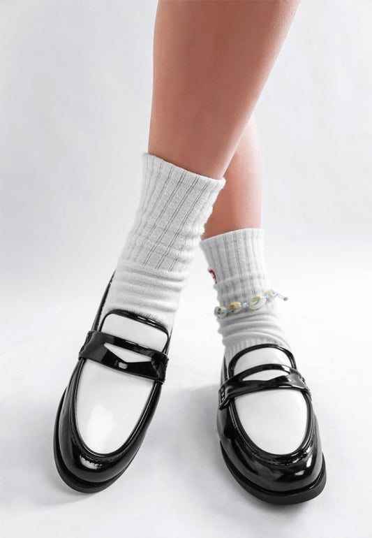 Black-and-white patent penny loafers with contrasting strap and round toe front view