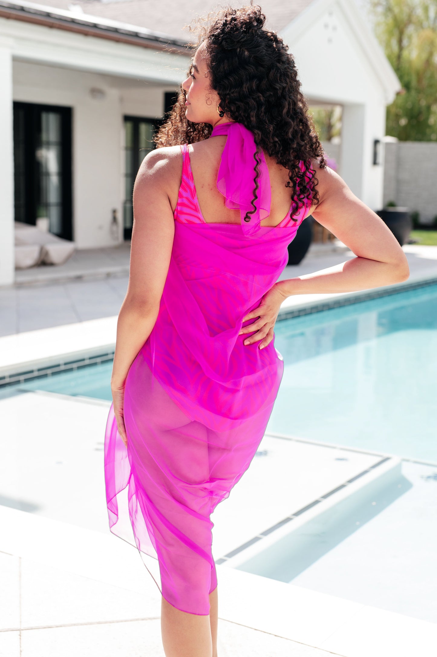 Back view of Wrapped in Summer Swim Cover styled as halter dress, pink mesh fabric flowing.