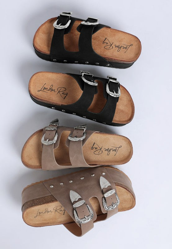 Faux leather flatform slip ons with carved buckle straps and round open toe - available in black and taupe.