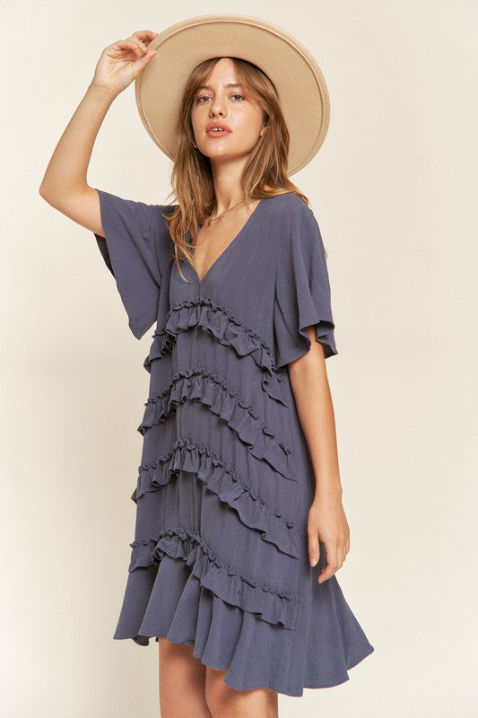 Front view of model wearing Gentry Tiered Ruffle Mini Dress in cement, styled for a casual summer look.