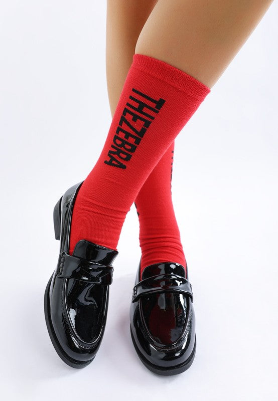 Front angle of model wearing Black Avery Patent Loafers highlighting penny strap and glossy finish.