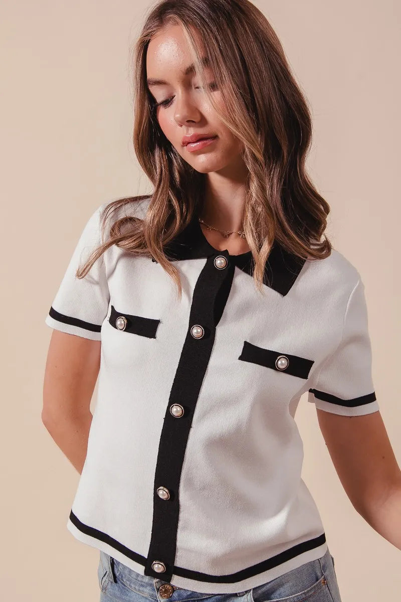 Close-up of Novah ivory knit sweater shirt with textured fabric, black trim, and button accents