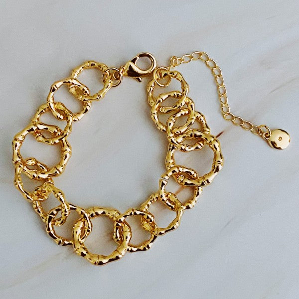 Textured gold chain bracelet with different-sized links shown in detailed flat lay