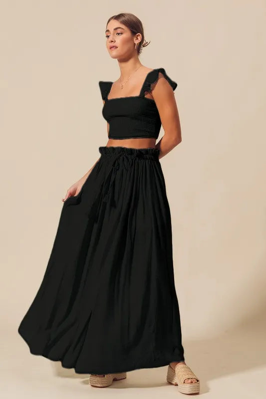 Full body side view of model in Kora Smocked Top and Flowy Black Maxi Skirt Set, showing ruffled sleeve and breezy skirt movement.