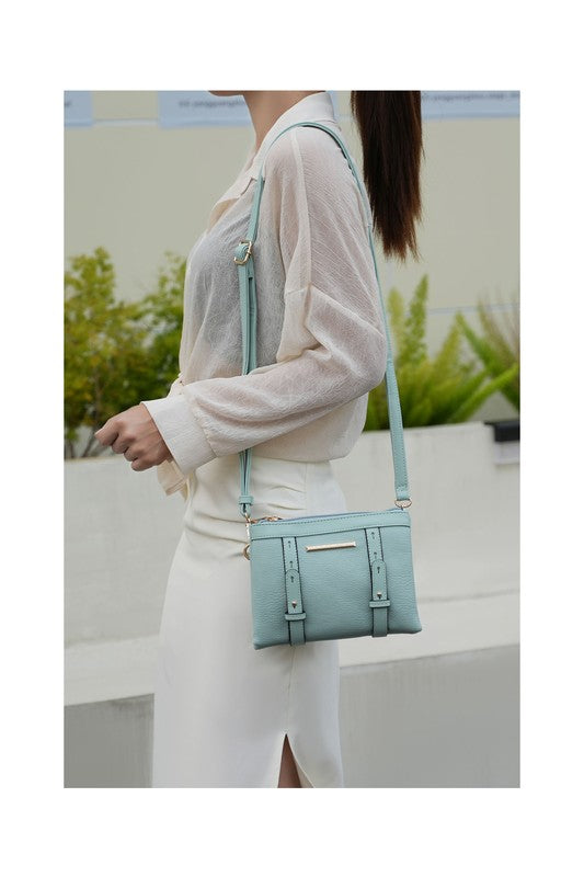 Woman holding seafoam Elsie crossbody bag over her shoulder, showing gold hardware and adjustable strap.
