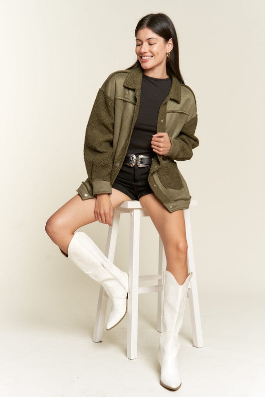 Olive Galina faux suede sherpa jacket worn while sitting on stool, casual cozy look.