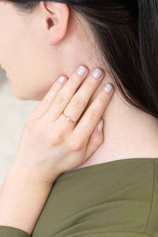 Becca White Stone Ring styled on woman’s hand, minimalist gold band with white stone