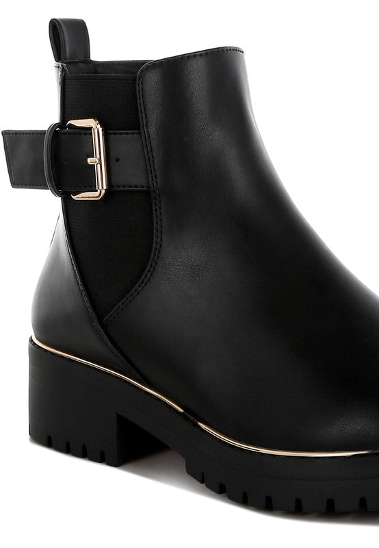 Close-up of black Antorin chunky buckle ankle boots showing textured vegan leather and buckle detail.