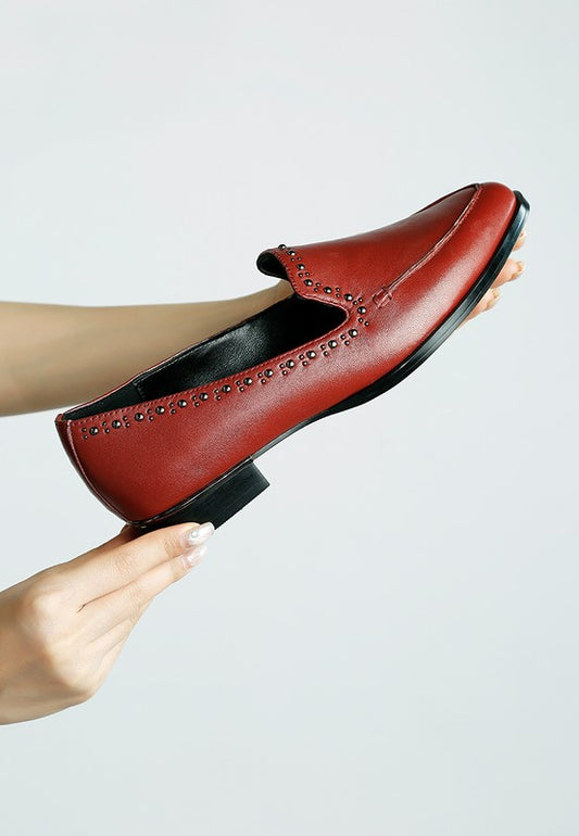 Woman holding burgundy Wolferton studded leather loafer in hand