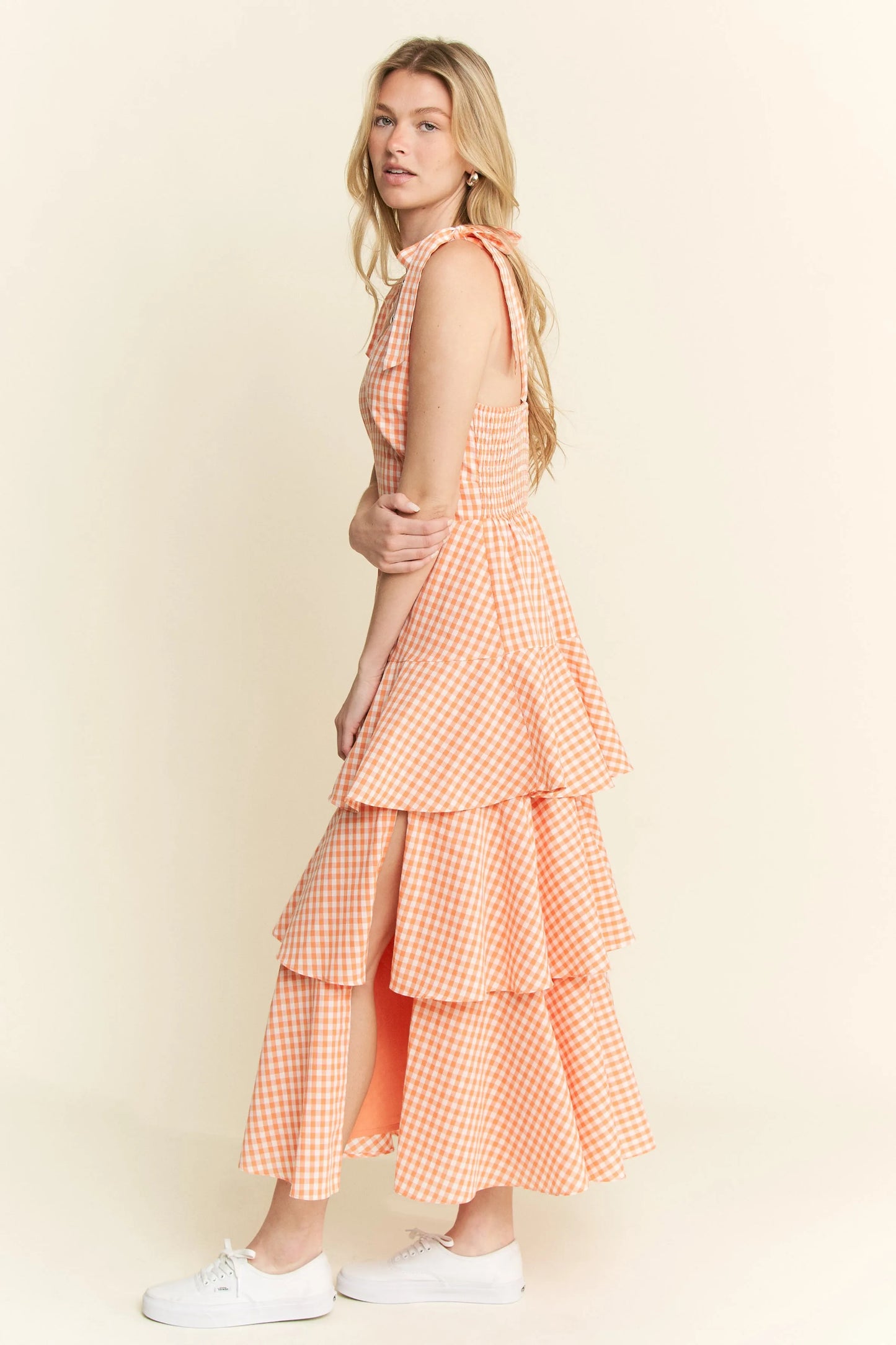Full body side view of model wearing Alice Gingham Tiered Midi Dress by Jade by Jane, featuring ruched back, halter ties, and layered ruffle skirt.