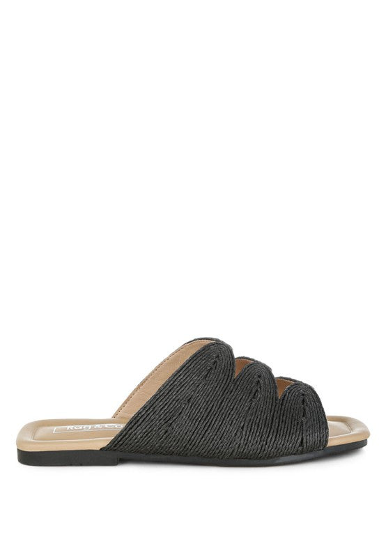 Outside side view of black Daisy Doe raffia flat featuring the cut work design, square toe, and woven raffia texture.