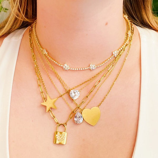 Woman wearing Locked In Shiny Heart Necklace layered with multiple gold necklaces showing trendy stacked style