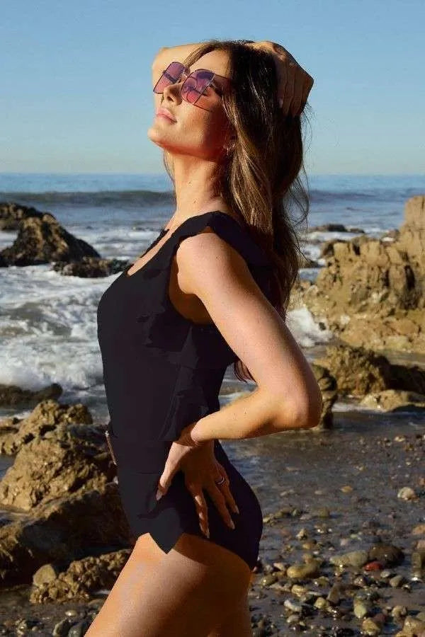 Side view of the Delany black one piece swimsuit showing ruffle detail and flattering silhouette.