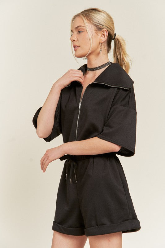 Side view of black Clover Plus Size romper with drop sleeves and rolled-hem shorts.
