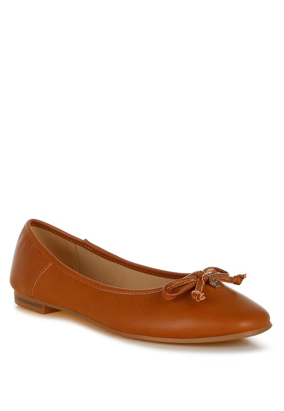 Tan vegan leather ballerinas with bow detail, cushioned insole, and round closed toe for feminine, versatile style.