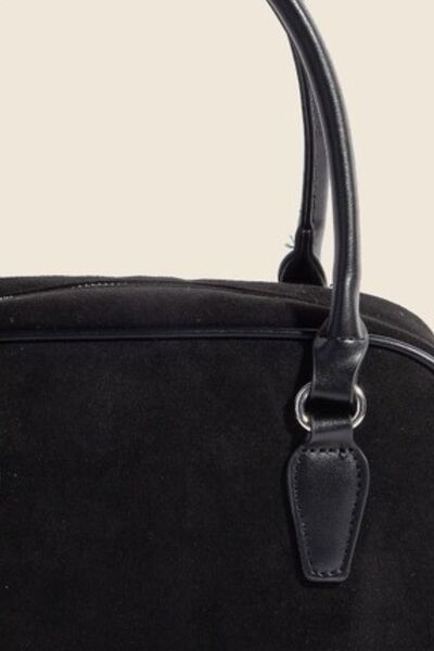 Close-up of Flavia handbag handle and gold hardware detailing on faux leather.