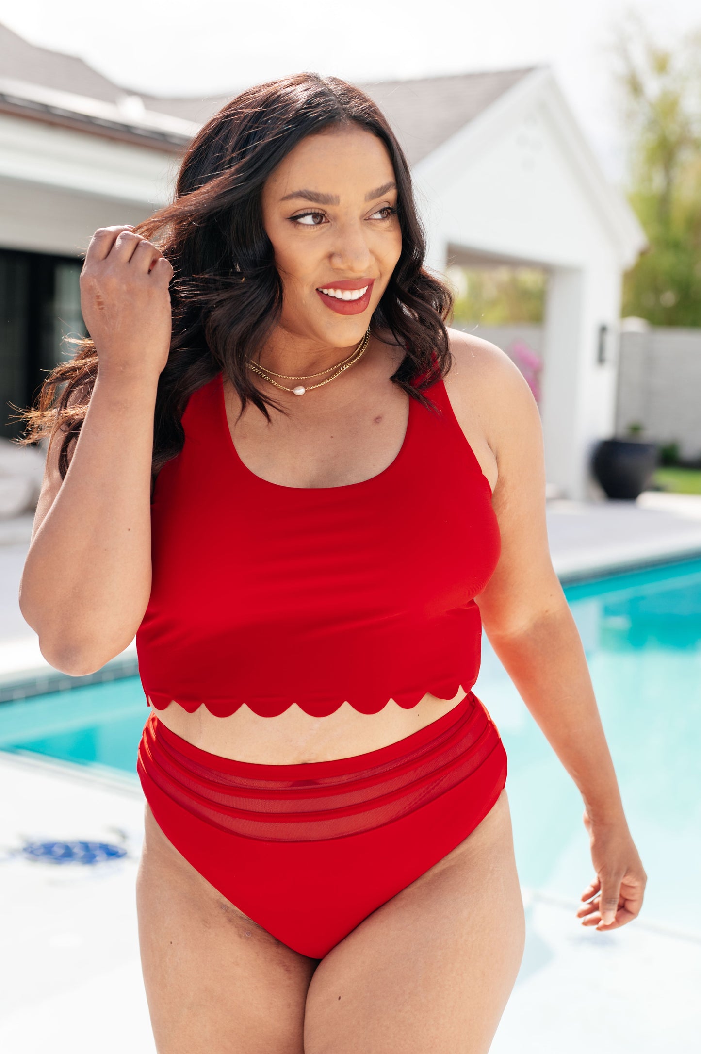 Women's red swim top with scalloped detailing, a round neckline, crossed straps, and a lined design for comfort and versatility.