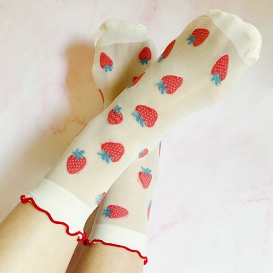 Woman wearing strawberry sheer socks with red fruit design and sheer white fabric.