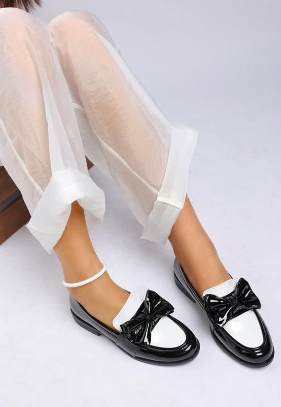 Model wearing Araminta Classic Chunky Bow Loafers in Black faux leather with low block heel
