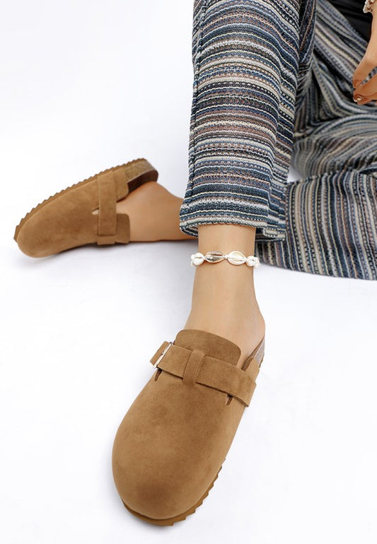 Tan Ratiha Mules worn by model, top front and side view showing gold buckle and subtle flat heel.
