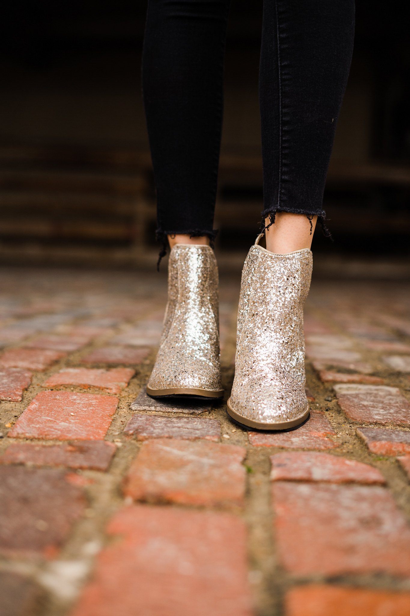 Model stepping forward in Fiera gold glitter booties.