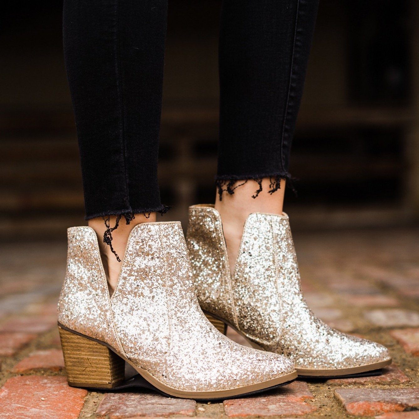Model wearing Fiera glitter booties with 3-inch heel, perfect for holiday looks.