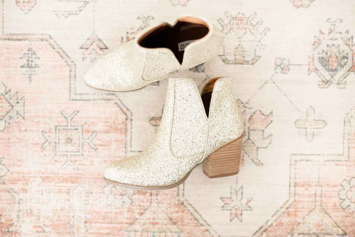 Top and side view of Fiera gold glitter booties showing vegan leather sparkle finish.