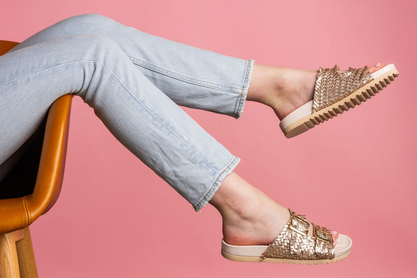 Cushioned sole and woven strap design of Karina champagne slides.