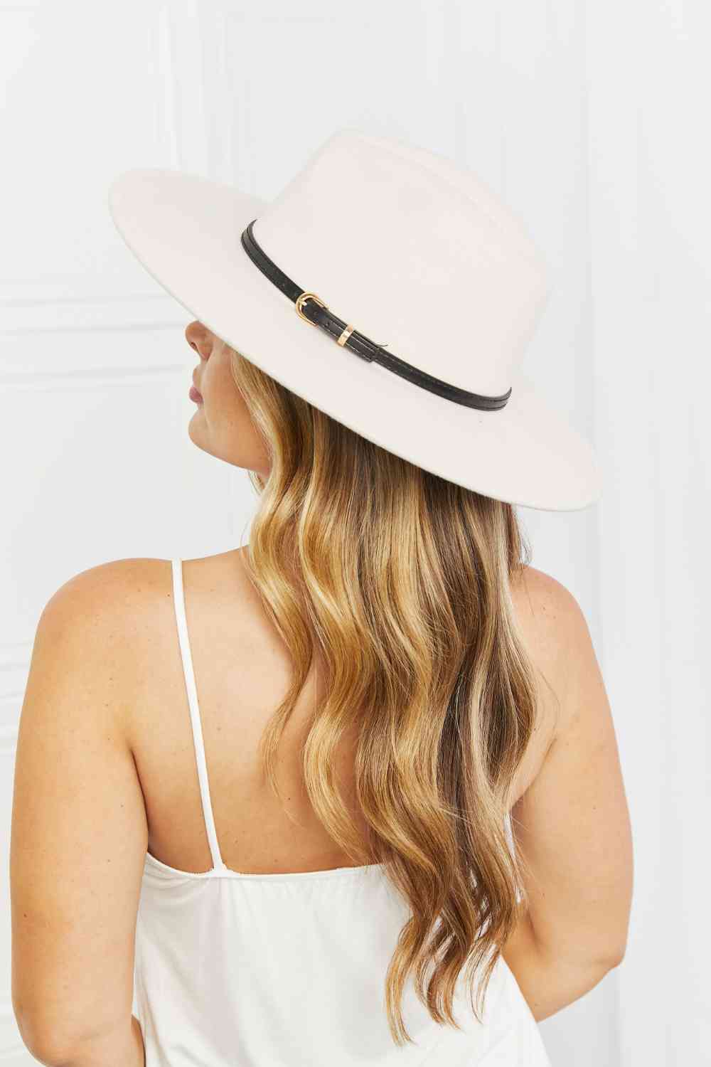 Beige fedora hat with a wide brim, a thin black belt detail with gold hardware, and adjustable straps for a customizable fit.