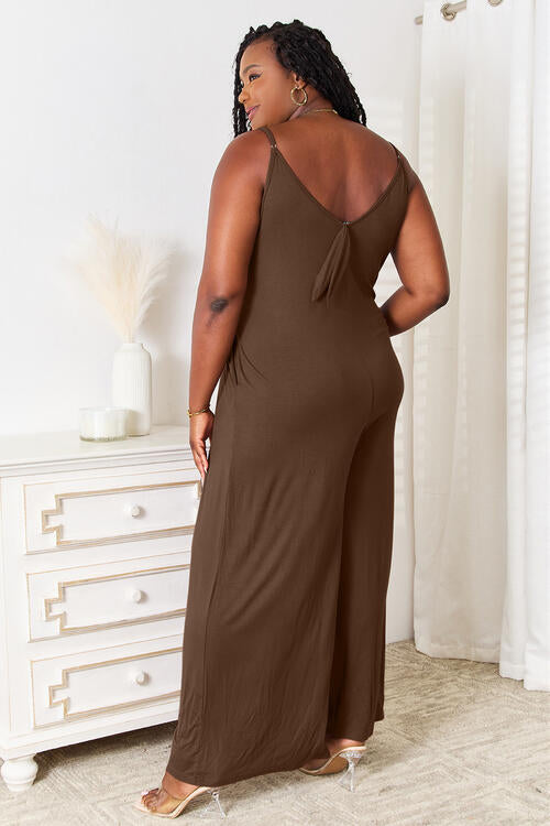 Back view of plus size mocha jumpsuit showing back tie detail and relaxed wide legs.