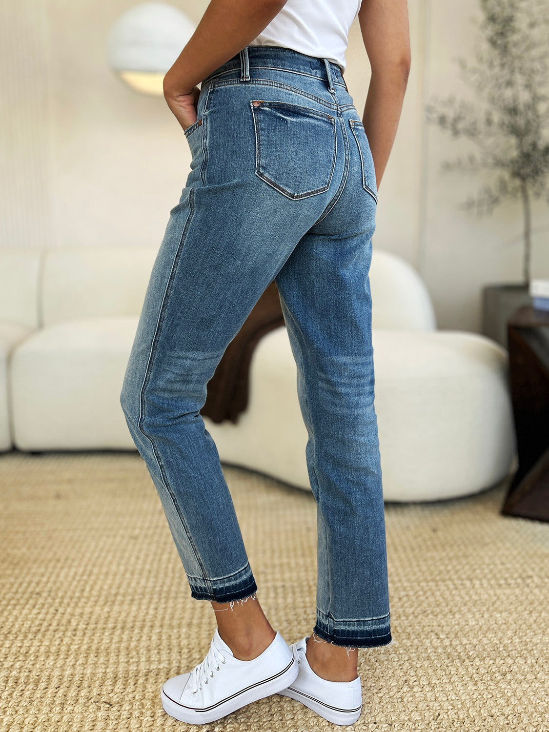 Medium wash mid-rise jeans with rigid fabric and released hem detail, featuring a relaxed fit and moderate stretch by Judy Blue.