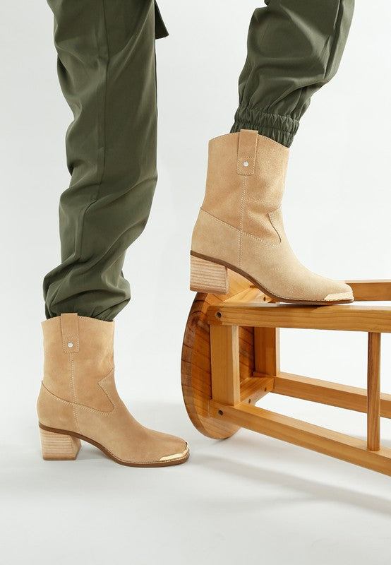 Beige Emberly boots on model with stacked heel and curved Western cut.