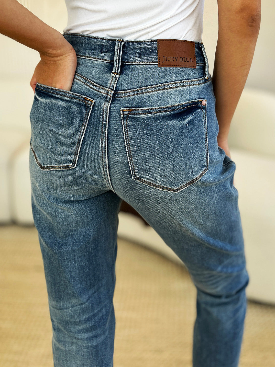 Medium wash mid-rise jeans with rigid fabric and released hem detail, featuring a relaxed fit and moderate stretch by Judy Blue.