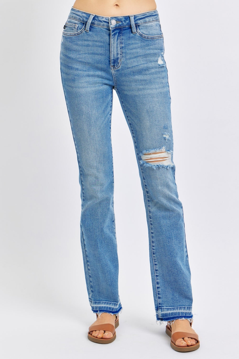 Medium wash mid-rise jeans with distressed detailing and destroyed hem, featuring a comfortable fit and moderate stretch.