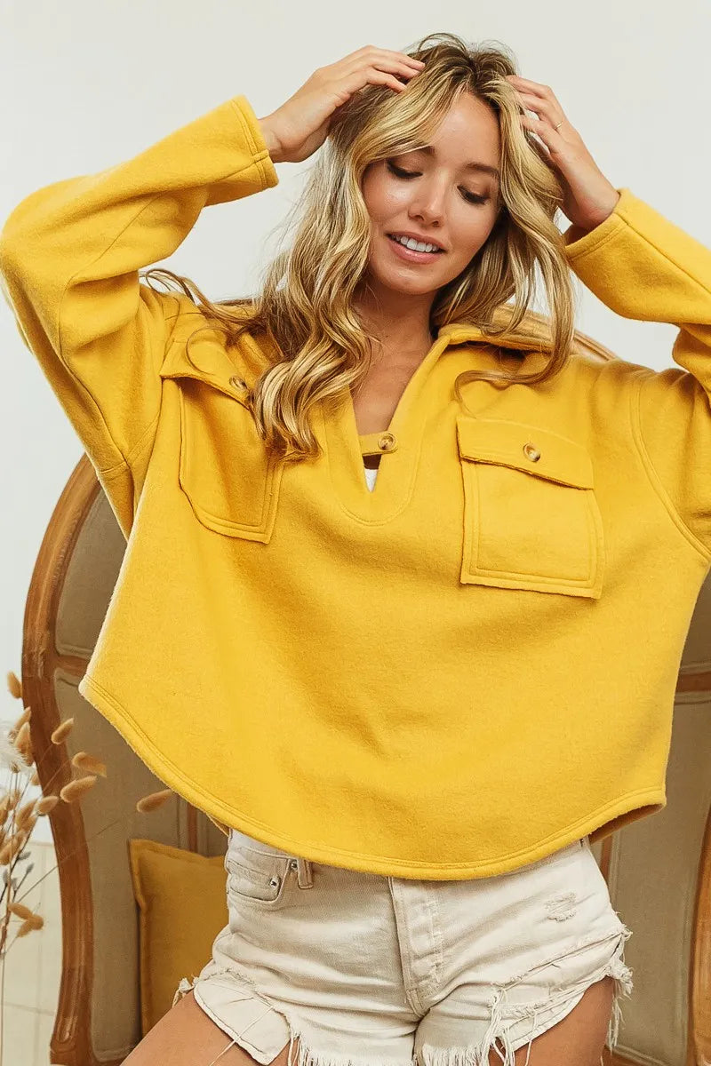 Model turned back angle showing collared neckline and flap pockets fleece sweatshirt in honey mustard.