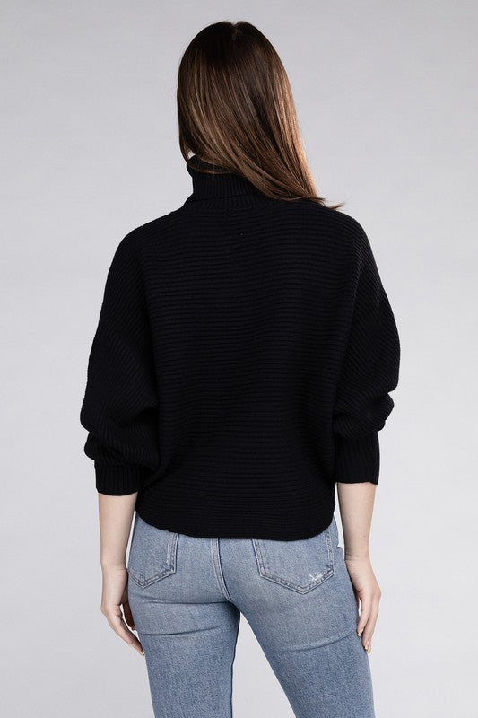 Black loose fitting turtleneck sweater, with ribbed knit texture, dolman sleeves, and raw hem detailing.