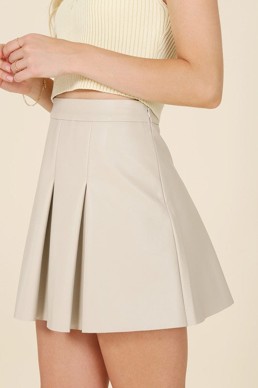 Ivory vegan leather pleated mini skirt with 4 pin tucks on the front and back for added style. Features a zipper closure.