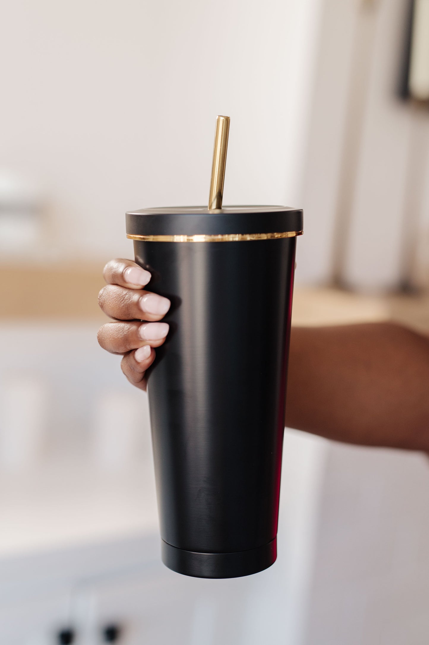 Black tumbler with gold accents, 25 oz capacity, made of double-layer stainless steel, includes a matching straw and cleaning brush.