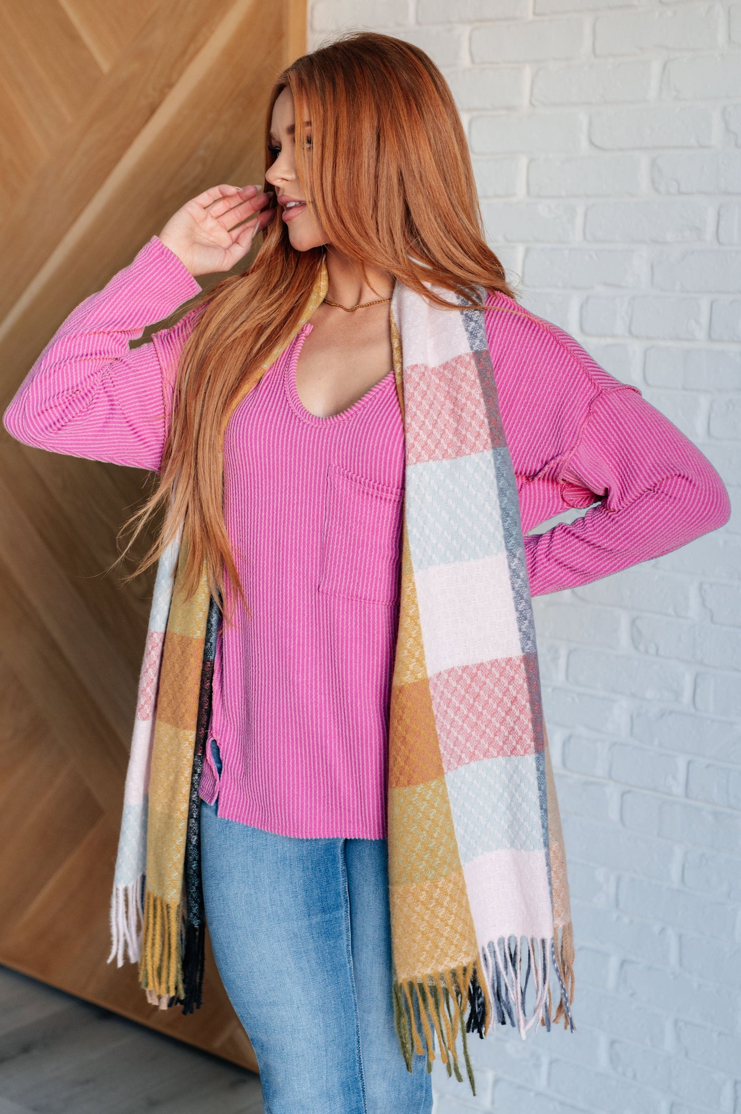 Women's cozy checkered fringe scarf in pink, yellow and gray, made from warm brushed fabric with playful fringe. Versatile for layering as a scarf or shawl to elevate any outfit.