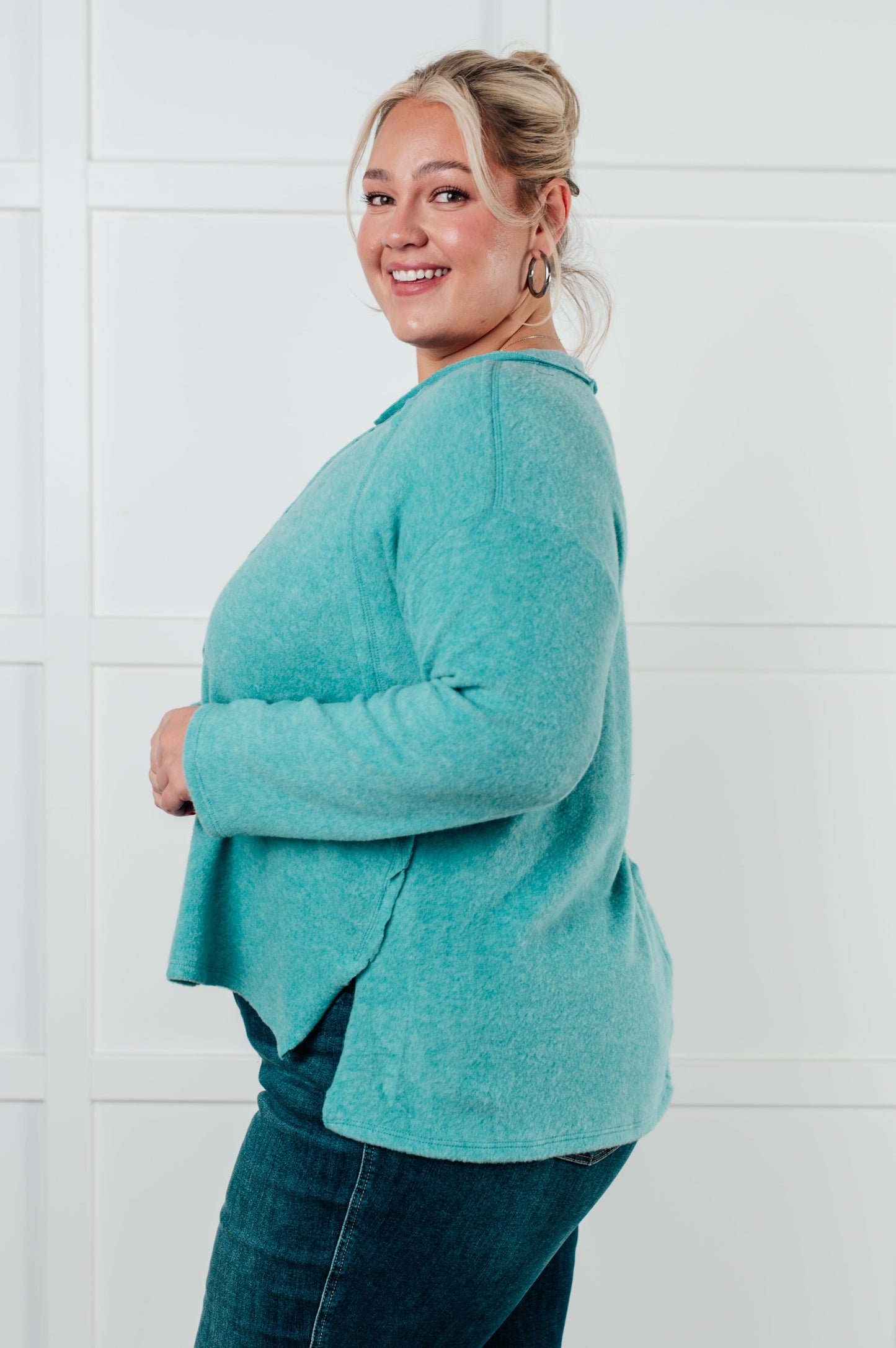 Women's Brushed Hacci Sweater in dusty teal featuring a round neckline, drop shoulders, stepped hemline, side slits, and raw seams. 